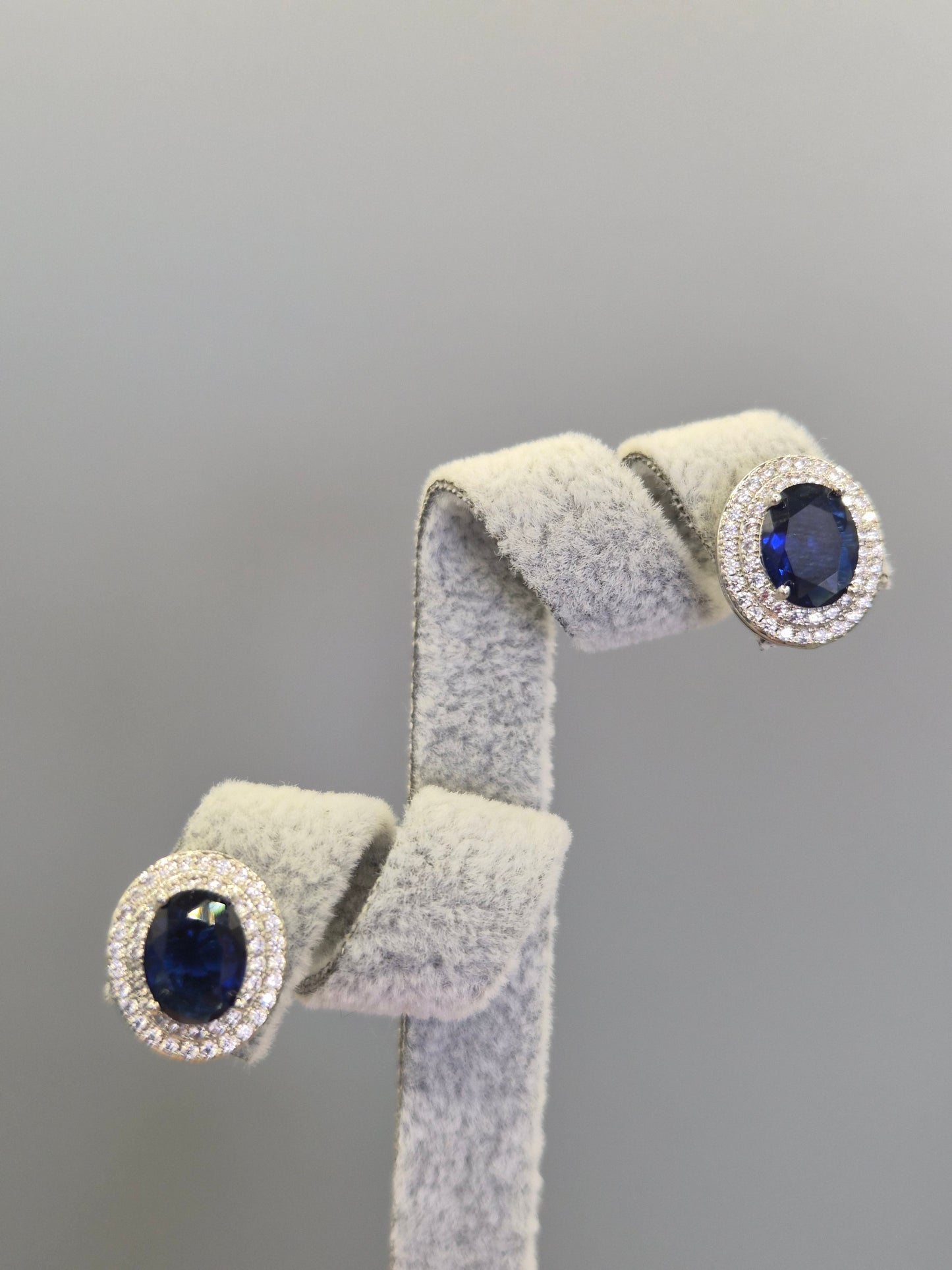 Oval Blue Center Stone Surrounded By Double Row of Round Brilliant Cut Cubic Zirconia Stud Earrings